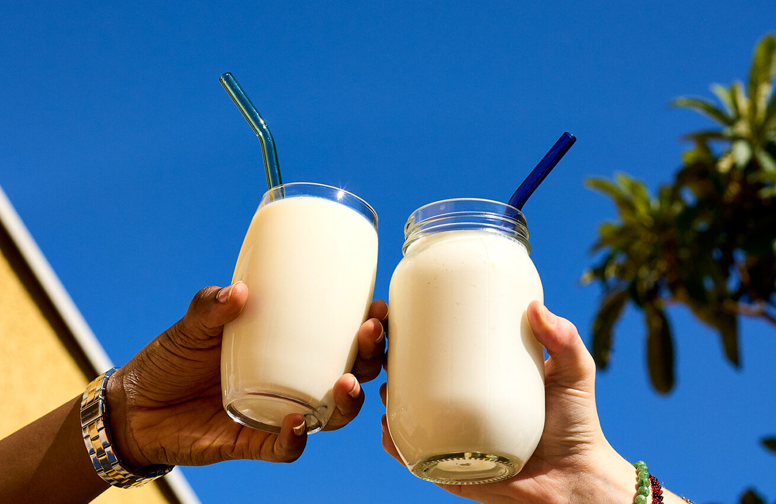 Two hands holding glasses of yoghurt drink